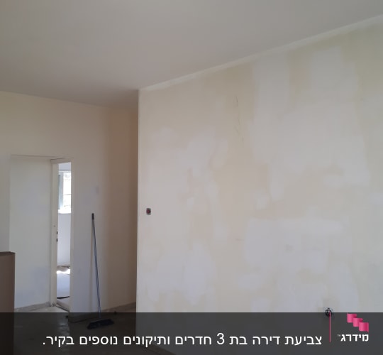 קיר צבוע חלקית עם סימני תיקון, מטאטא על הרצפה
